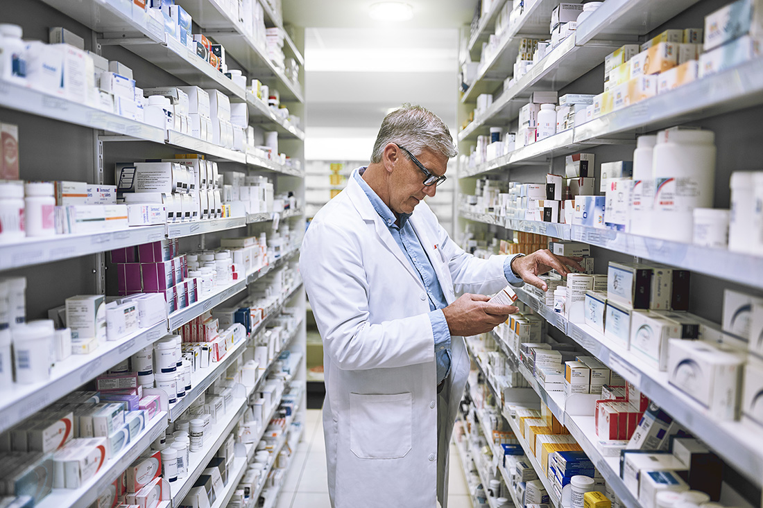 En apotekare letar fram en medicin på hyllan.